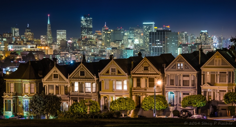 Painted Ladies of San Francisco at night glow against the backdrop of the sparkling San Francisco skyline. 