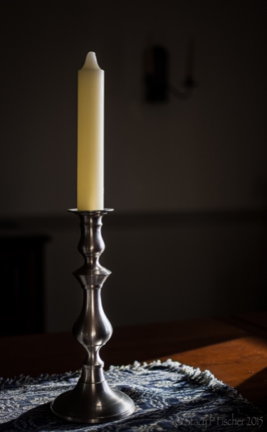 Pewter candlestick illuminated by sidelight.
